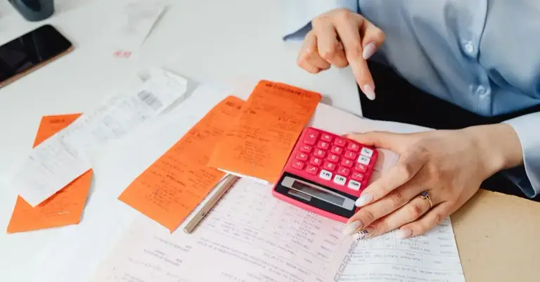 Mãos calculando orçamento sobre recibos e documentos financeiros