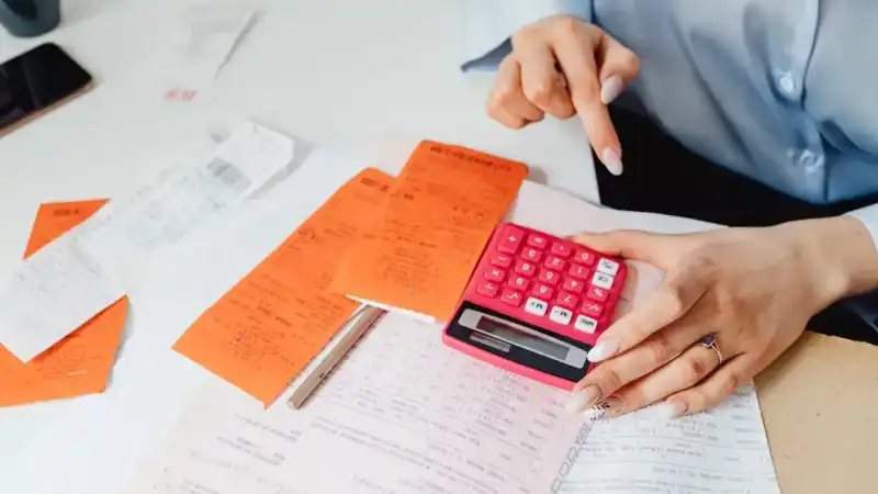 Mãos calculando orçamento sobre recibos e documentos financeiros