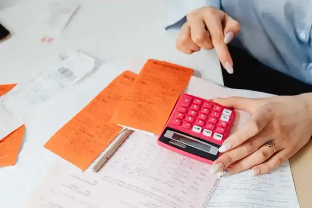 Mãos calculando orçamento sobre recibos e documentos financeiros
