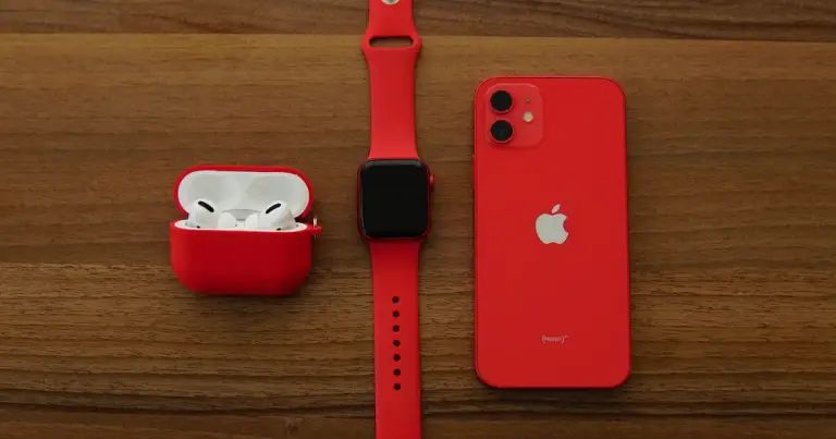 Smartwatch, fones sem fio e smartphone vermelhos sobre mesa de madeira — gadgets e wearables