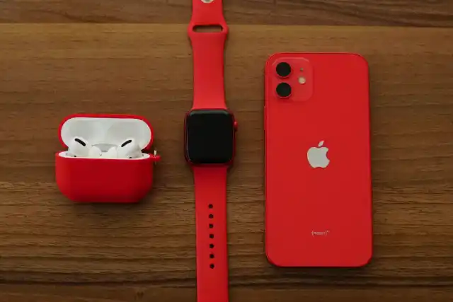 Smartwatch, fones sem fio e smartphone vermelhos sobre mesa de madeira — gadgets e wearables
