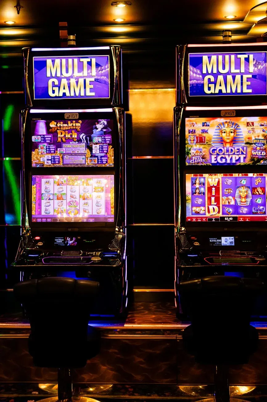 Máquinas caça-níqueis coloridas com vários jogos dentro de um ambiente de cassino animado à noite.